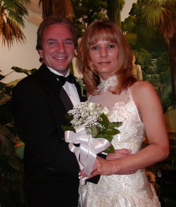 A smiling couple holding a white bouquet